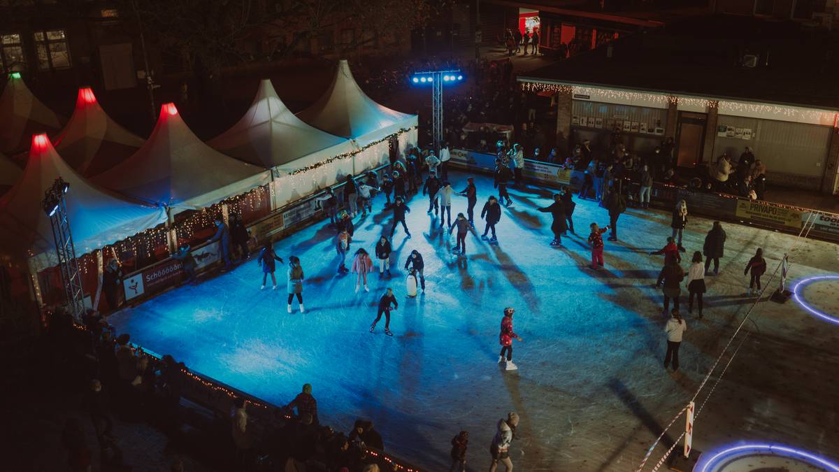 Die Eislaufbahn am Lugacci in Elmshorn am Abend: Schlittschuhläufer zwischen beleuchteten Zelten